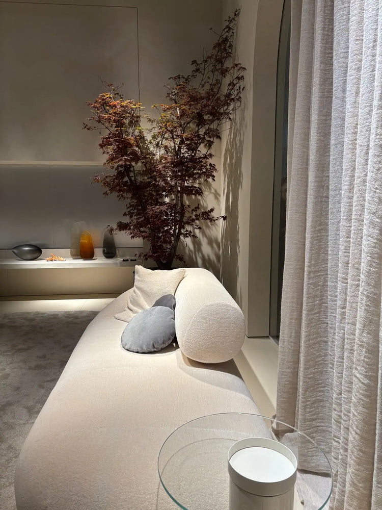 Elegant modern living room with curved cream sofa and subtle colourful accents.